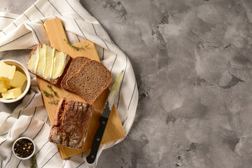 Wall Mural - Wooden board with bread slices and bowl of fresh butter on grey background