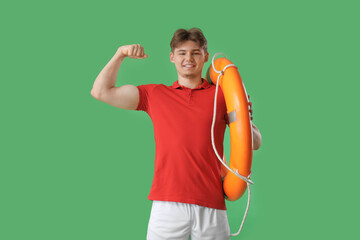 Canvas Print - Male lifeguard with ring buoy showing muscles on green background