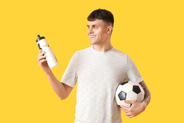 Sticker - Sporty young man with bottle of water and soccer ball on yellow background