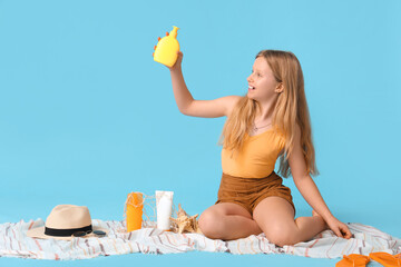 Wall Mural - Beautiful girl taking sunscreen cream on blue background