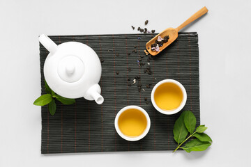 Wall Mural - Teapot with cups, wooden scoop of dry tea and leaves on white background