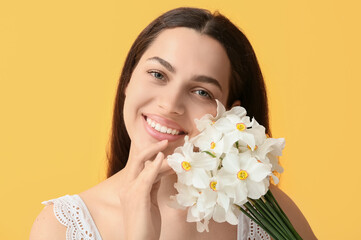 Wall Mural - Happy young woman with bouquet of white daffodil flowers on yellow background