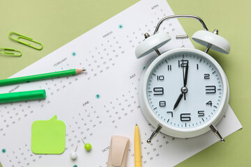 Wall Mural - Calendar with alarm clock and office stationery on green background