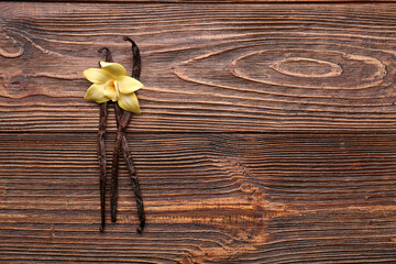 Wall Mural - Beautiful yellow vanilla flower and sticks on wooden background