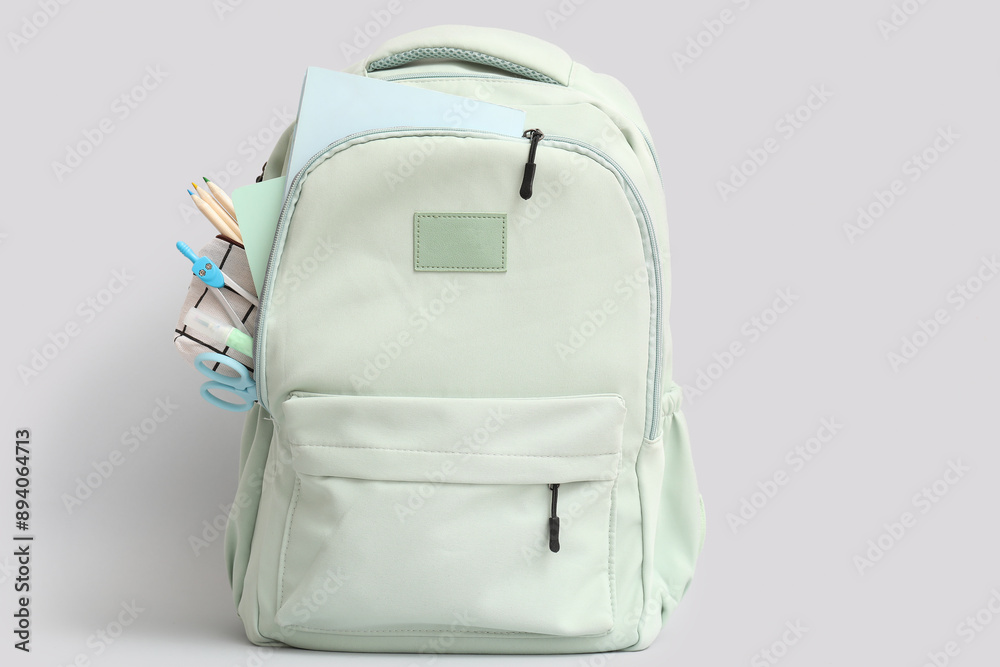 Grey school backpack with stationery and notebooks on white background