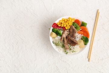 Wall Mural - Bowl of tasty rice, chicken, vegetables and chopsticks on light background