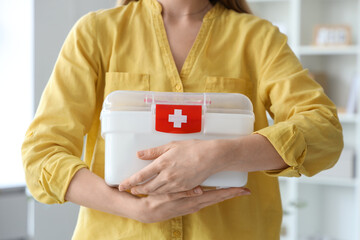 Wall Mural - Woman with first aid kit at home, closeup