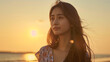 © bephoto - 夕暮れのビーチで物思いにふける若い女性
