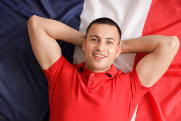 Wall Mural - Young man lying on flag of France, top view