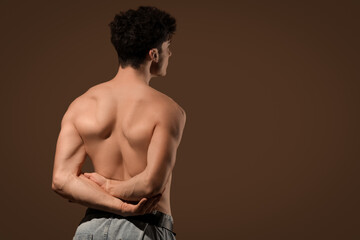 Sticker - Muscular young man on dark brown background, back view