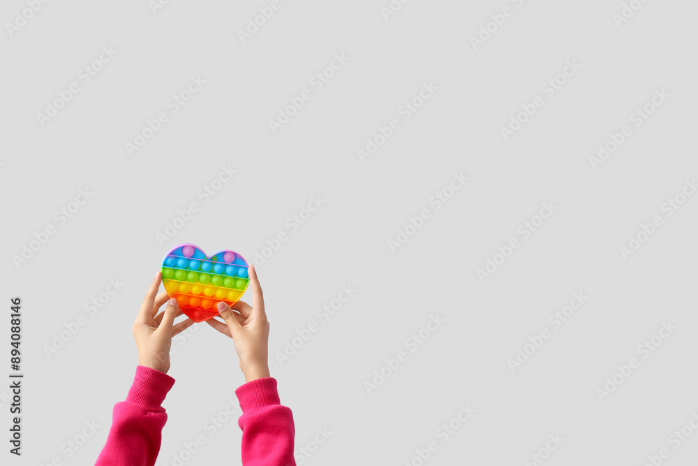 Child with pop it fidget toy on light background