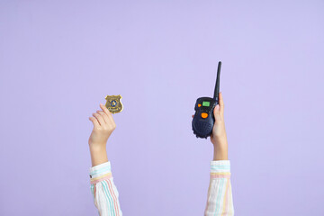 Wall Mural - Child with policeman's badge and two-way radio on lilac background