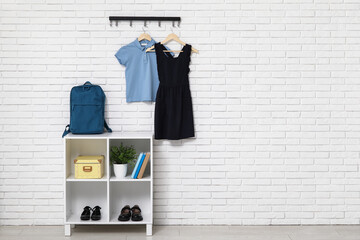 Wall Mural - Rack with backpack, books and stylish school uniform hanging on light brick wall