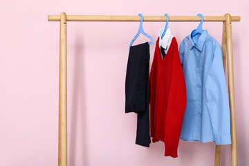 Wall Mural - Wooden rack with stylish school uniform against pink wall