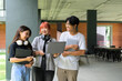 © Parichat - Group of Happy Students Collaborating Outdoors with Laptops and Notebooks in a Modern Campus Setting