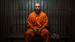 © halo - A man dressed in orange sits on a bench of a prison cell alone, looking at the camera, jail or imprisonment concept image.