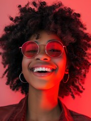 Happy woman with red sunglasses and curly hair laughing under red light