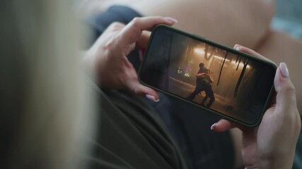 Poster - close up of woman holding mobile phone in hands and watching action movie lying on sofa. smartphone 