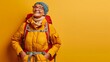 © Farid - Middle aged woman mountaineer gear ready on yellow background.