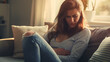 © Наталья Мирошниченко - Woman with stomach pain sitting on sofa holding stomach with expression of suffering