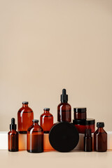 Wall Mural - Set of brown glass bottles with essential oils on stand on beige background