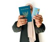 © Siti Fatonah - A blurred woman holding Indonesian Passport and Indonesian identity cards (KTP) isolated on white background