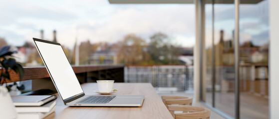 A laptop computer on a table on an apartment balcony with city view. outdoors workspace