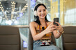 © bongkarn - A beautiful Asian female tourist using her smartphone while waiting for her flight in the airport.