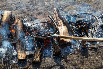 Asan-si, Chungcheongnam-do, South Korea - October 22, 2022: High angle view of chestnuts roasting on two grills and wood fire in the yard of Oeam Folk village
