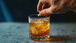 © Victoria Sharratt - Hand over glass, spiking a drink, dropping in pills. Whiskey with ice in a glass on a marble table.