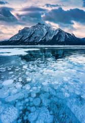 Wall Mural - Natural bubbles frost on frozen Abraham Lake with rocky mountains in winter at Canada