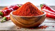 © kansak01 - Vibrant red chili powder heap in a rustic wooden bowl, contrasting beautifully with the pure white background, evoking spicy aromas.