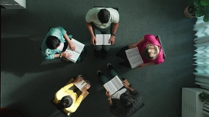 Wall Mural - Top view of skilled diverse prayer clasping hand and praying to god while sitting at chair in circle. Top down aerial view of people folded hand while sitting with opened bible on laps. Symposium.