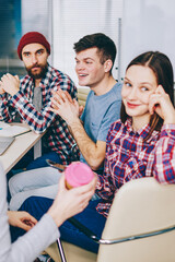Fototapete - Group of casual dressed students communicating with each other having coffee break in office.Successful young people working together on development common startup project sitting at meeting table