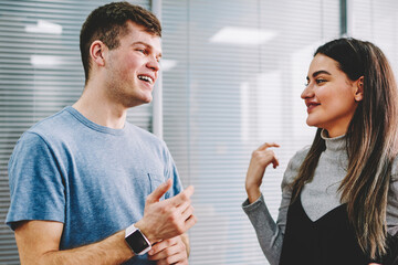 Fototapete - Group of cheerful colleagues laughing while talking with each other during work break in modern office.Positive young people in casual wear discussing creative ideas for new common project