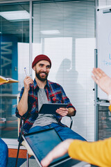 Fototapete - Positive successful young people dressed in casual wear discussing plan of collaboration sitting in office.Cheerful hipster guys laughing and communicating with each other about working process