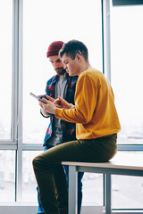 Fototapete - Busy young people dressed in casual wear collaborating with each other using modern devices and internet connection in modern office loft.Group of employees of design company cooperating on project