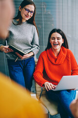 Fototapete - Emotional positive young woman with modern laptop computer laughing during collaboration with colleagues on new project in office.Cheerful successful young people having fun during working process