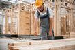 © standret - Standing, marking plank by pencil. Industrial worker in wooden warehouse