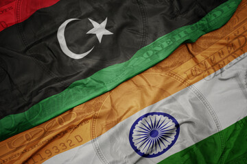 Wall Mural - waving colorful flag of india and national flag of libya on the dollar money background. finance concept.