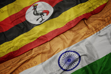 Wall Mural - waving colorful flag of india and national flag of uganda on the dollar money background. finance concept.