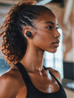 © Ivan - Portrait of a black woman at the gym, wearing a black cropped exercise t-shirt and wireless headphones in her ears, vertical close-up side view. Healthy lifestyle