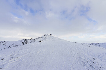 Winter and morning view of two tourists standing on snow covered hill near Kerid Crater, Iceland
