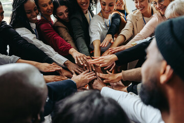 Wall Mural - diverse coworkers putting hands in for a unified team huddle at work