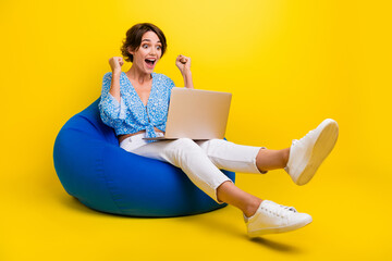 Poster - Full size photo of crazy woman wear blue top sitting on bean bag look at laptop shout win lottery isolated on yellow color background