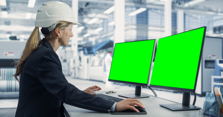 Aufkleber - Caucasian Female Technician In Hardhat Working on a Desktop Computer with Green Screen Chromakey Mock-Up Display in a Factory Office. Autonomous Technological Research and Development Facility.