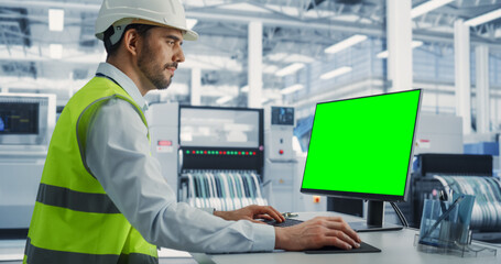 Aufkleber - Caucasian Male Industrial Engineer In Protective Gear Working on a Desktop Computer with Green Screen Chromakey on Display at an Electronics Factory. Technological Research and Development Center.