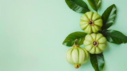 Wall Mural - Three vibrant green fruits accompanied by fresh leaves on a pastel green background, creating a serene and organic visual appeal.