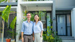 © VK Studio - A happy couple poses outside their modern home, surrounded by lush greenery, capturing a moment of pride and togetherness in their beautiful garden.