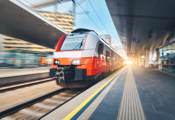 Wall Mural - high-speed passenger train moving at railway station at sunset